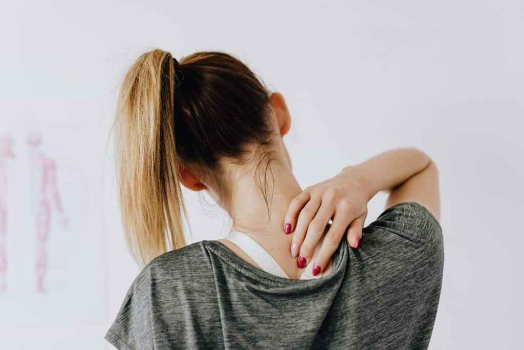 pexels-photo-4506105-4506105 A woman in casual clothing holds her neck, indicating pain or discomfort.